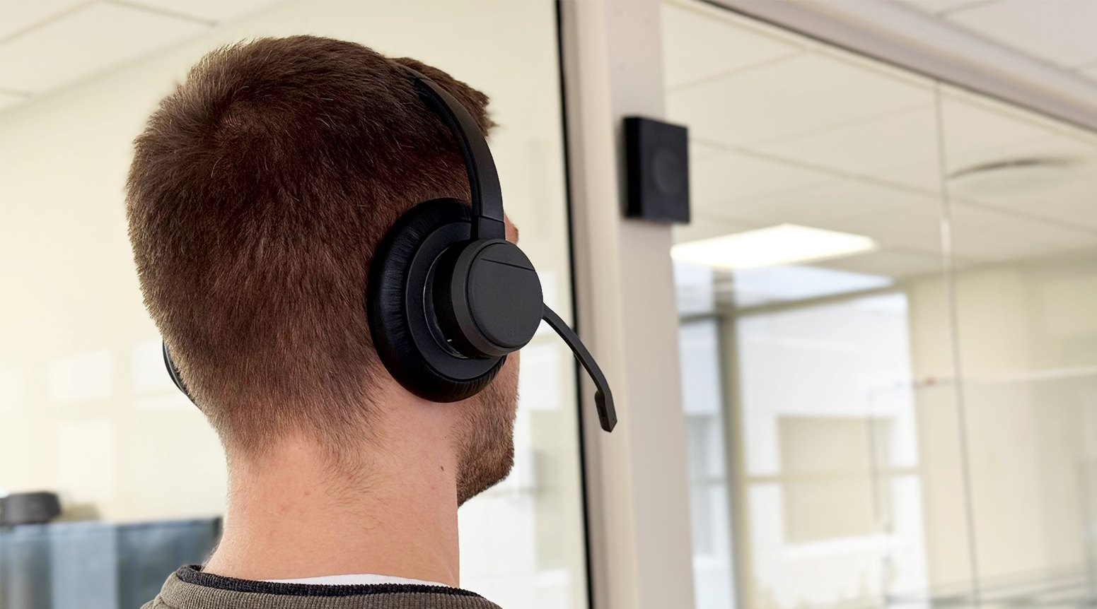 person wearing RTX Wireless Headset in office environment and Base Station mounted on wall